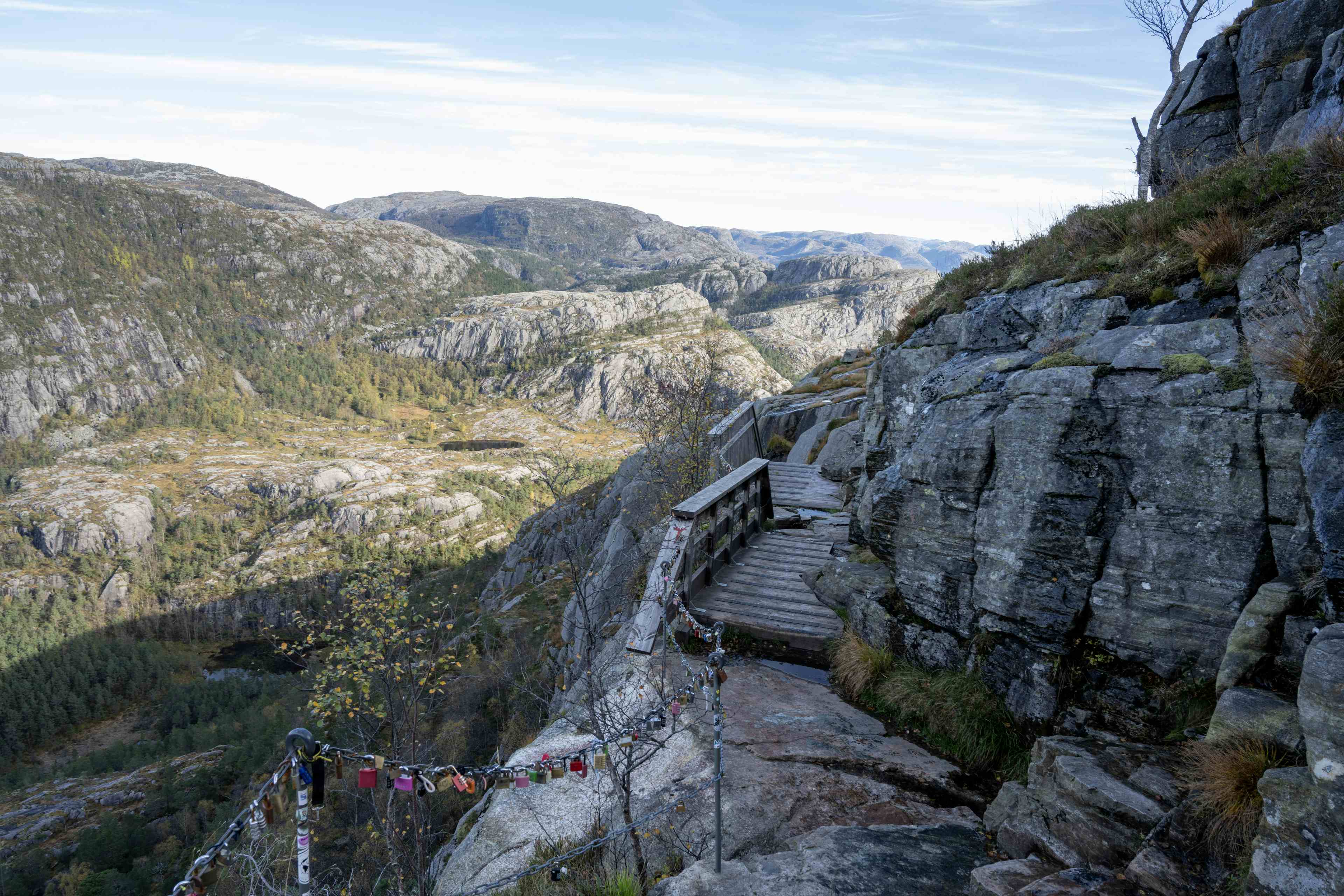 People standing on a mountain plateaut more than 600 metres above fjord level. Blue sky and sunny day. Steep mountains and fjord. Guided hike to Preikestolen