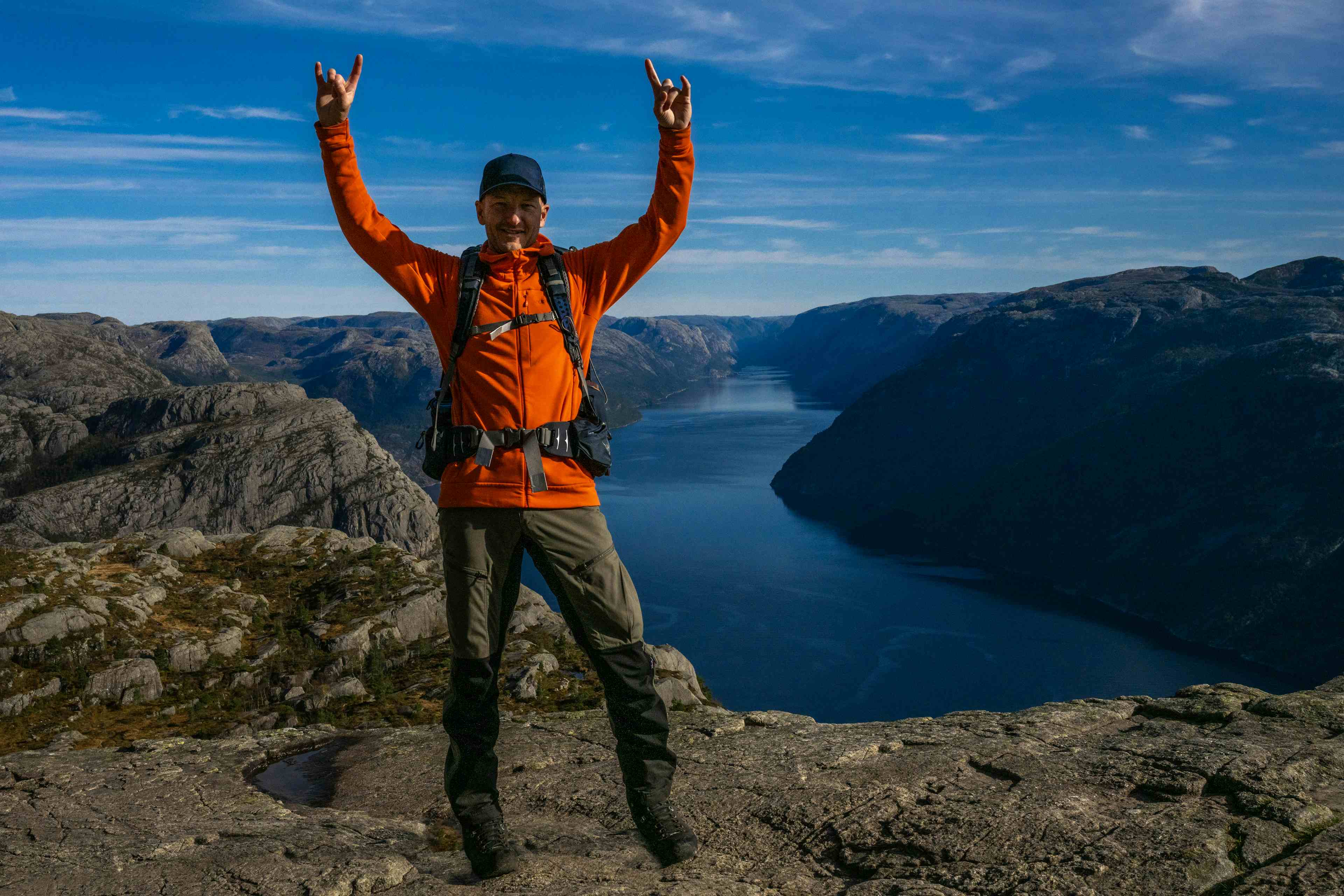 People standing on a mountain plateaut more than 600 metres above fjord level. Blue sky and sunny day. Steep mountains and fjord. Guided hike to Preikestolen