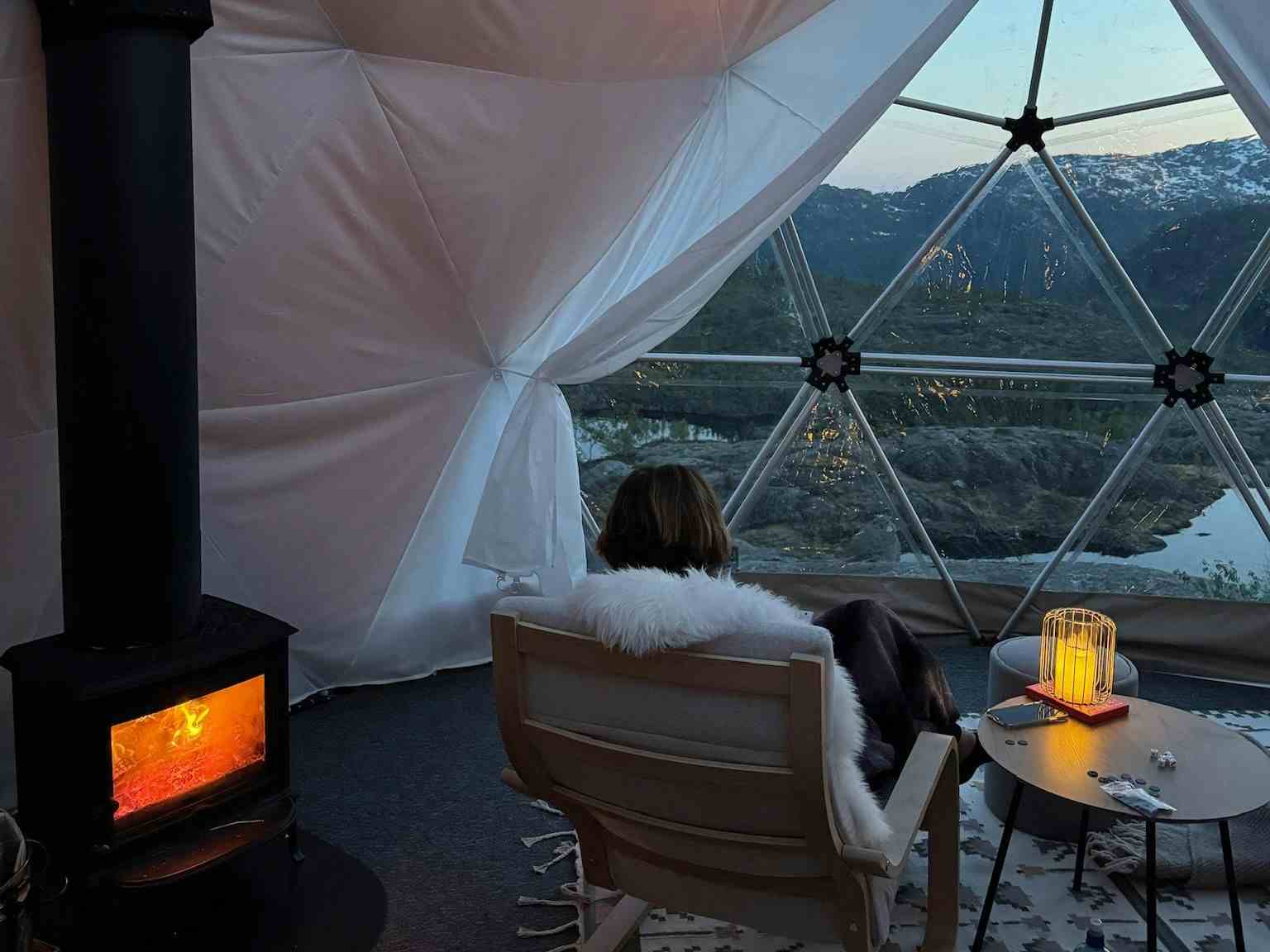 To personer som sitter inne i glamping-teltet og nyter utsikten over Saudafjellet.