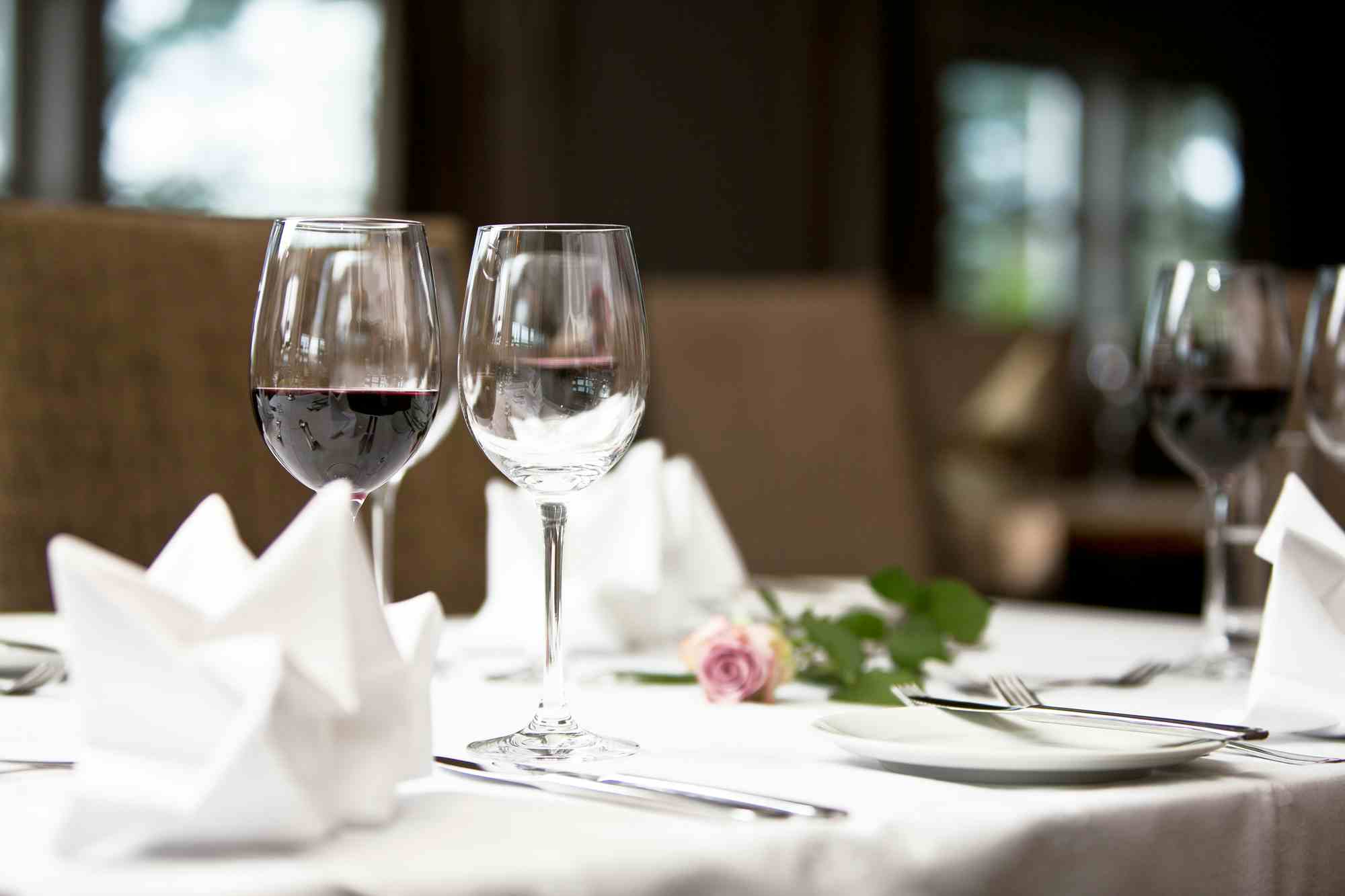 Food plates, kitchen staff, hotel restaurant, set table with white tablecloth, wine glasses on table