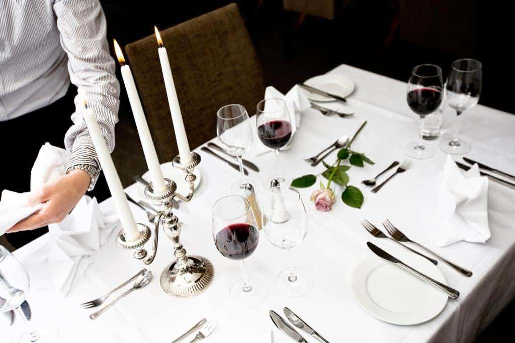 Food plates, kitchen staff, hotel restaurant, set table with white tablecloth, wine glasses on table
