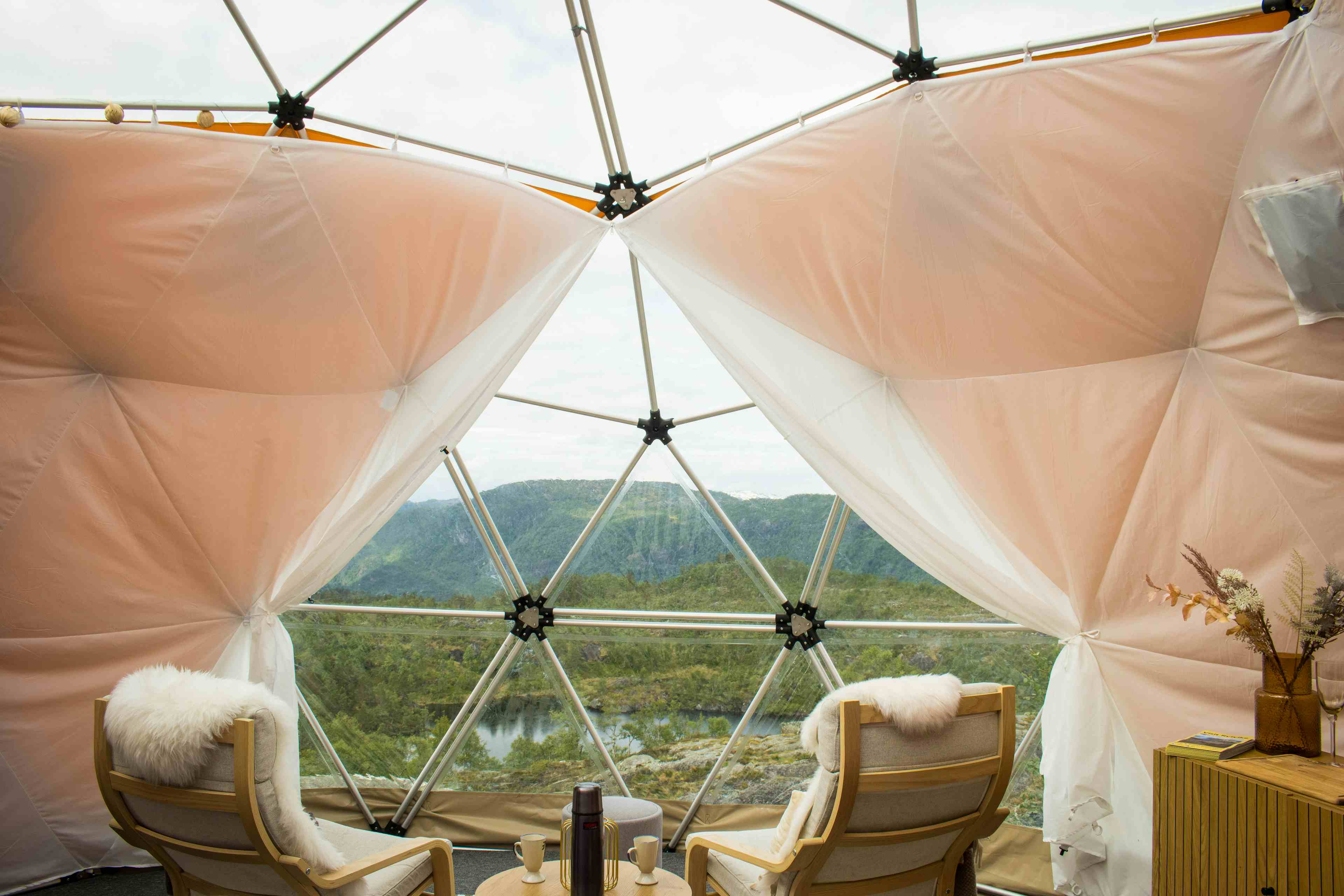 To personer som sitter inne i glamping-teltet og nyter utsikten over Saudafjellet.