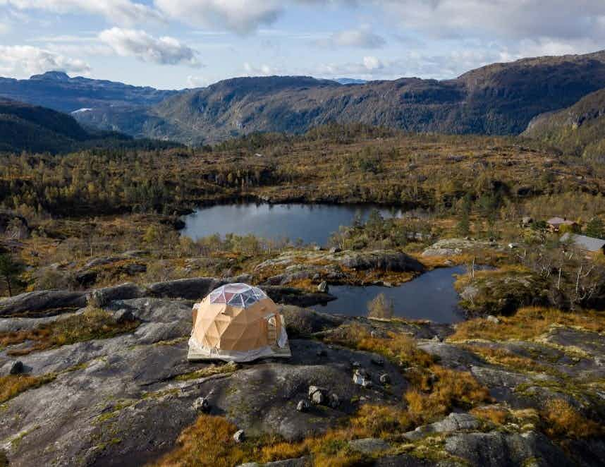 To personer som sitter inne i glamping-teltet og nyter utsikten over Saudafjellet.