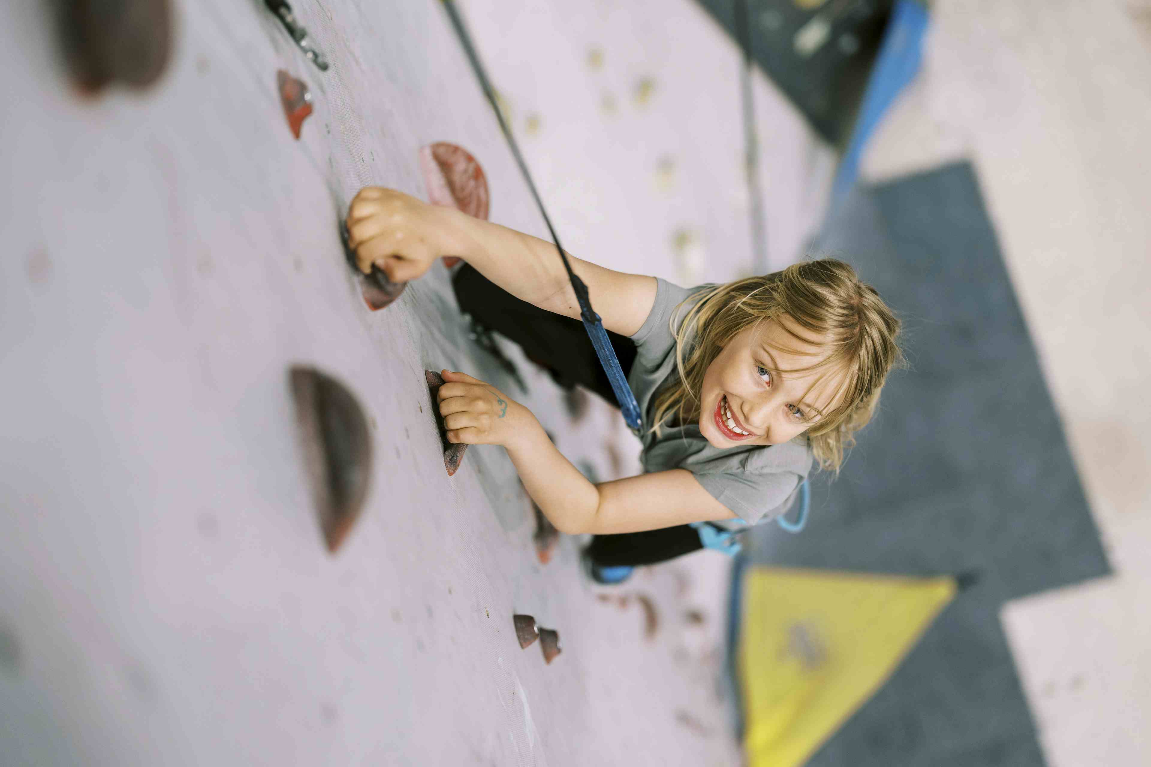 Small child climbing with harness in inside playpark Playground