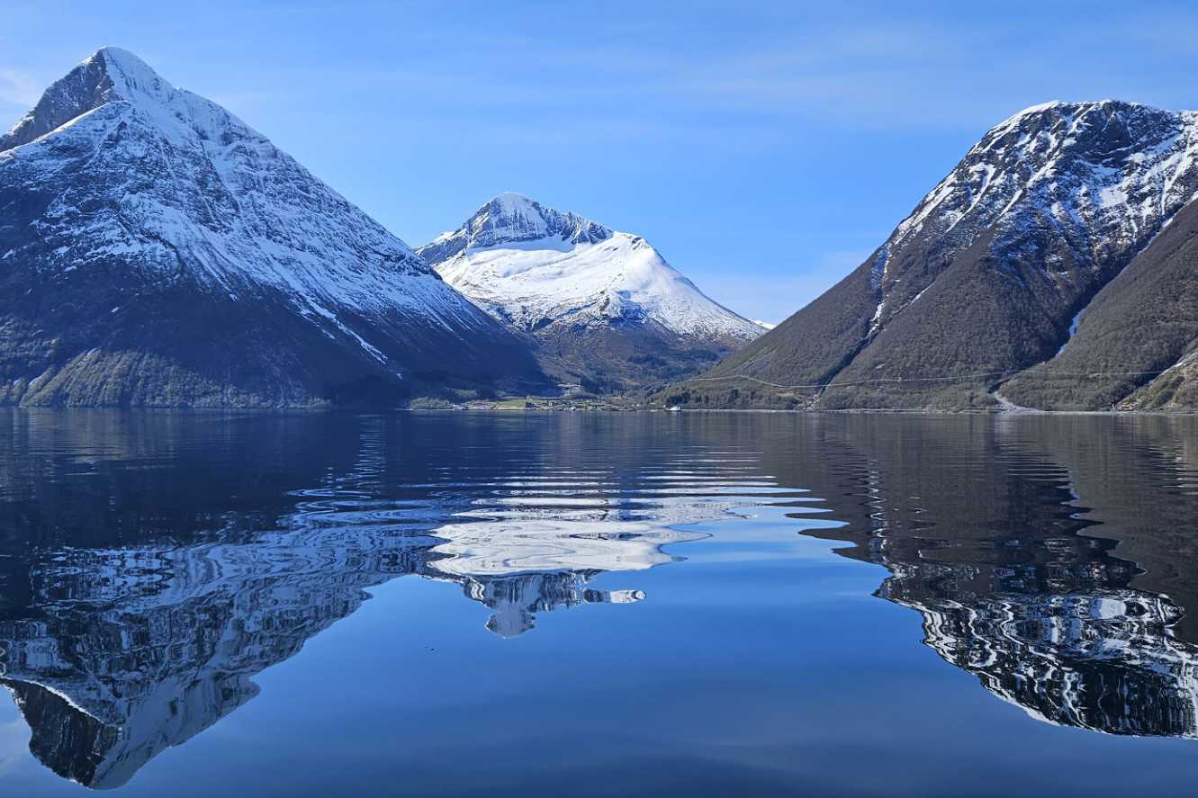 Fra båten ser man inn til vakre Hjørundfjord omkranset av høye fjell.