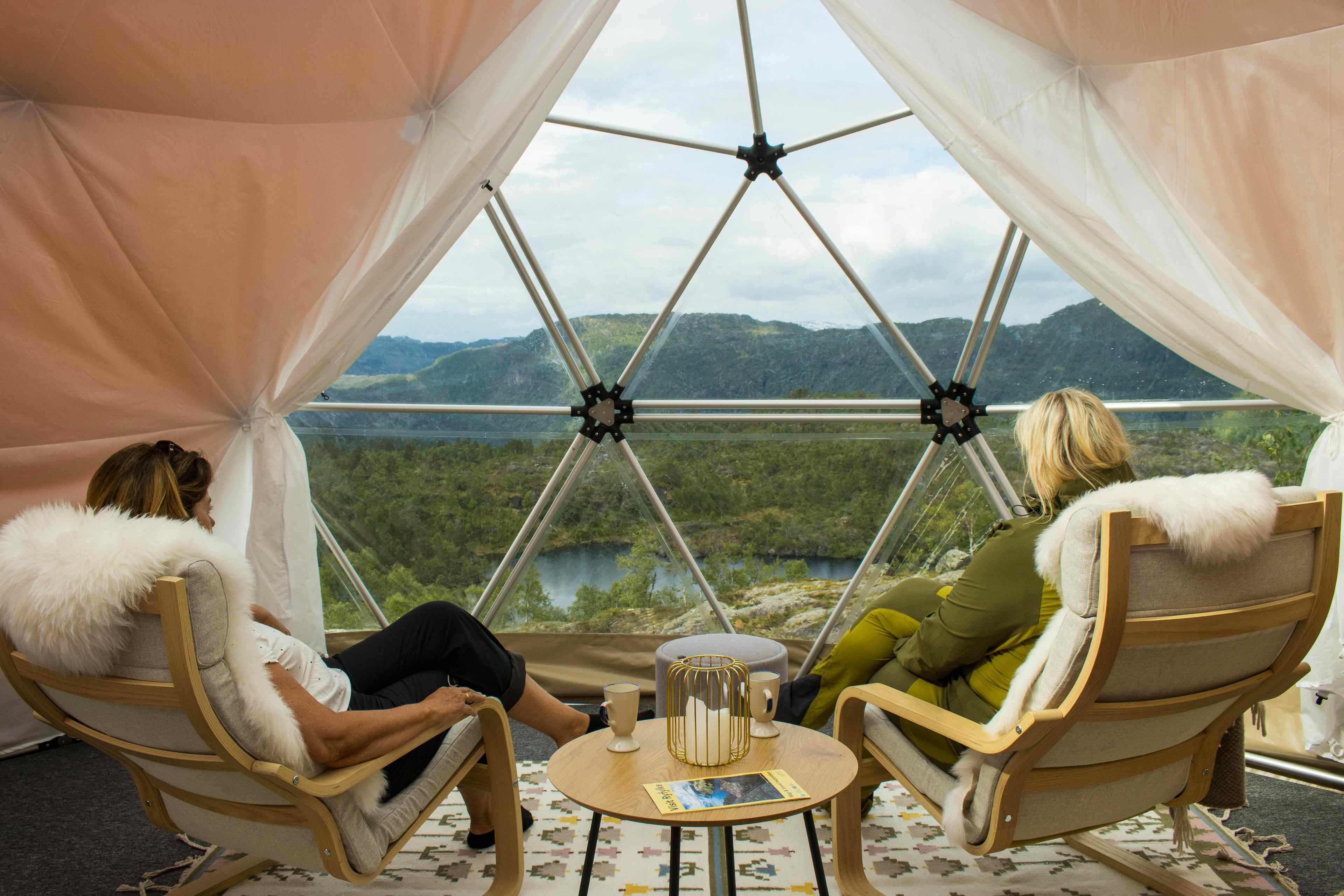 To personer som sitter inne i glamping-teltet og nyter utsikten over Saudafjellet.